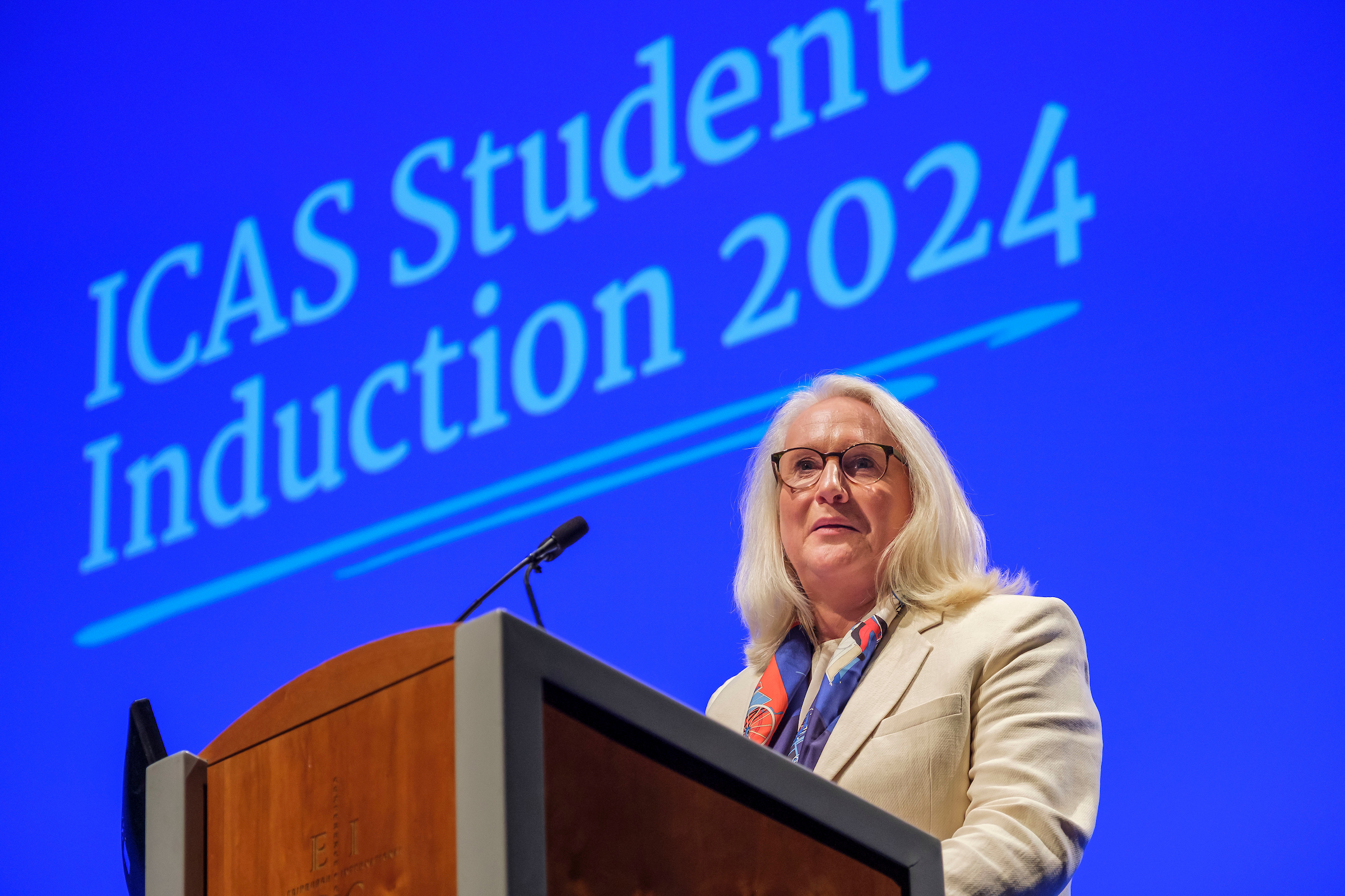 Woman in suit jacket speaking from behind a lectern